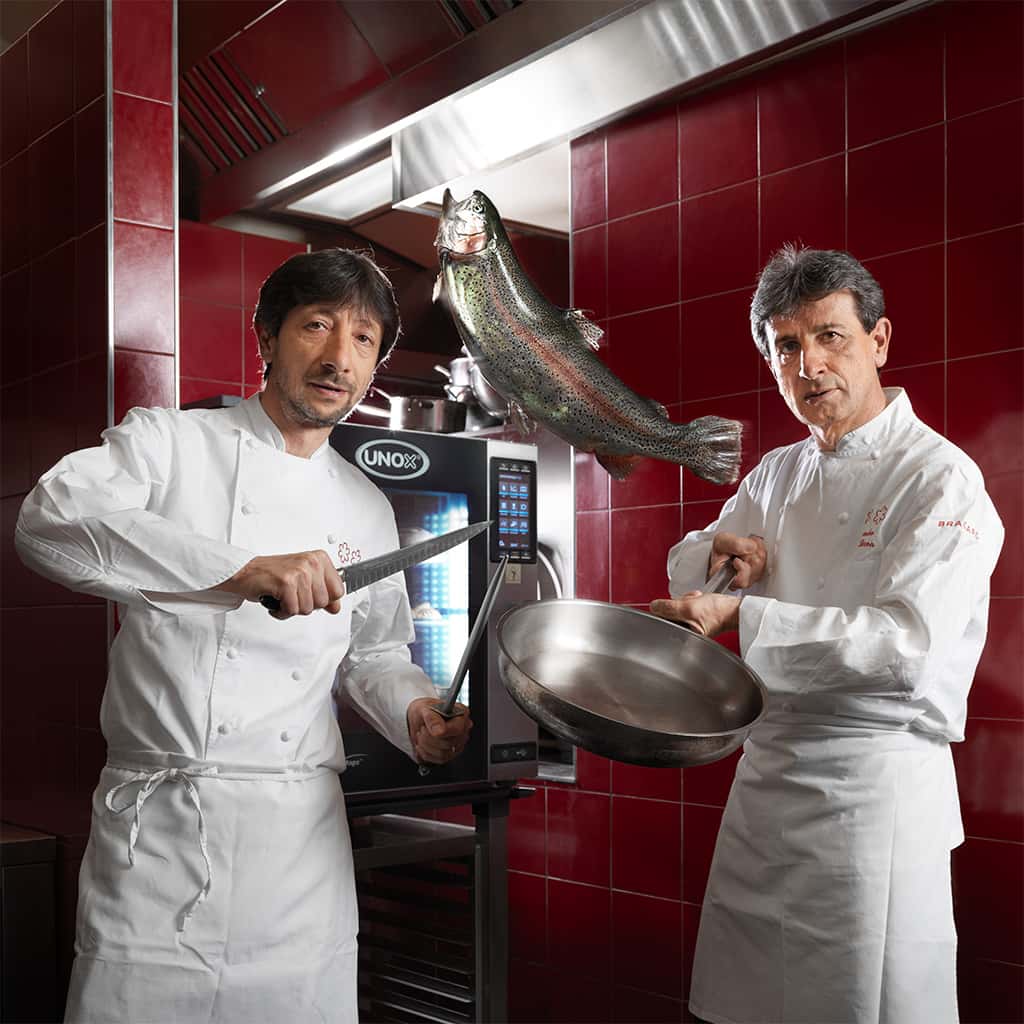 Male chef in a red tiled kitchen opening the door of an Unox combi oven.