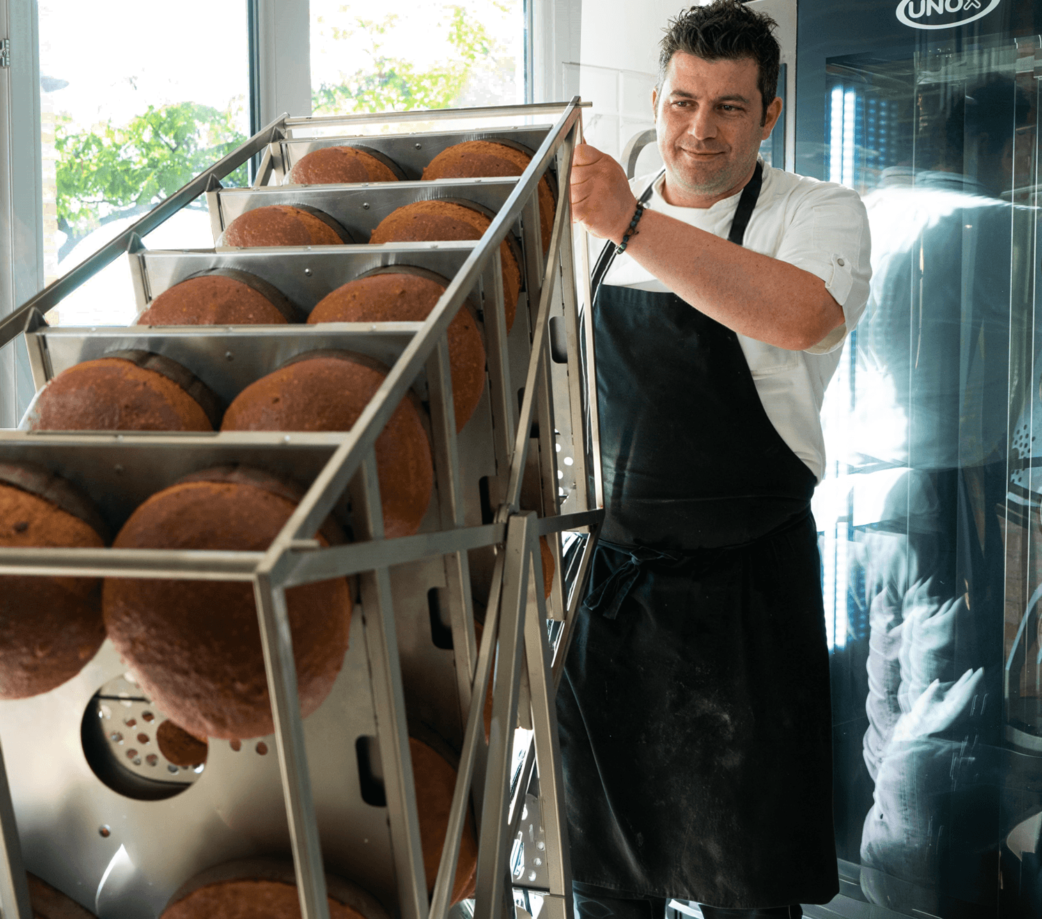 Chef inverting a full load of panettone on a Unox commercial combi oven trolley