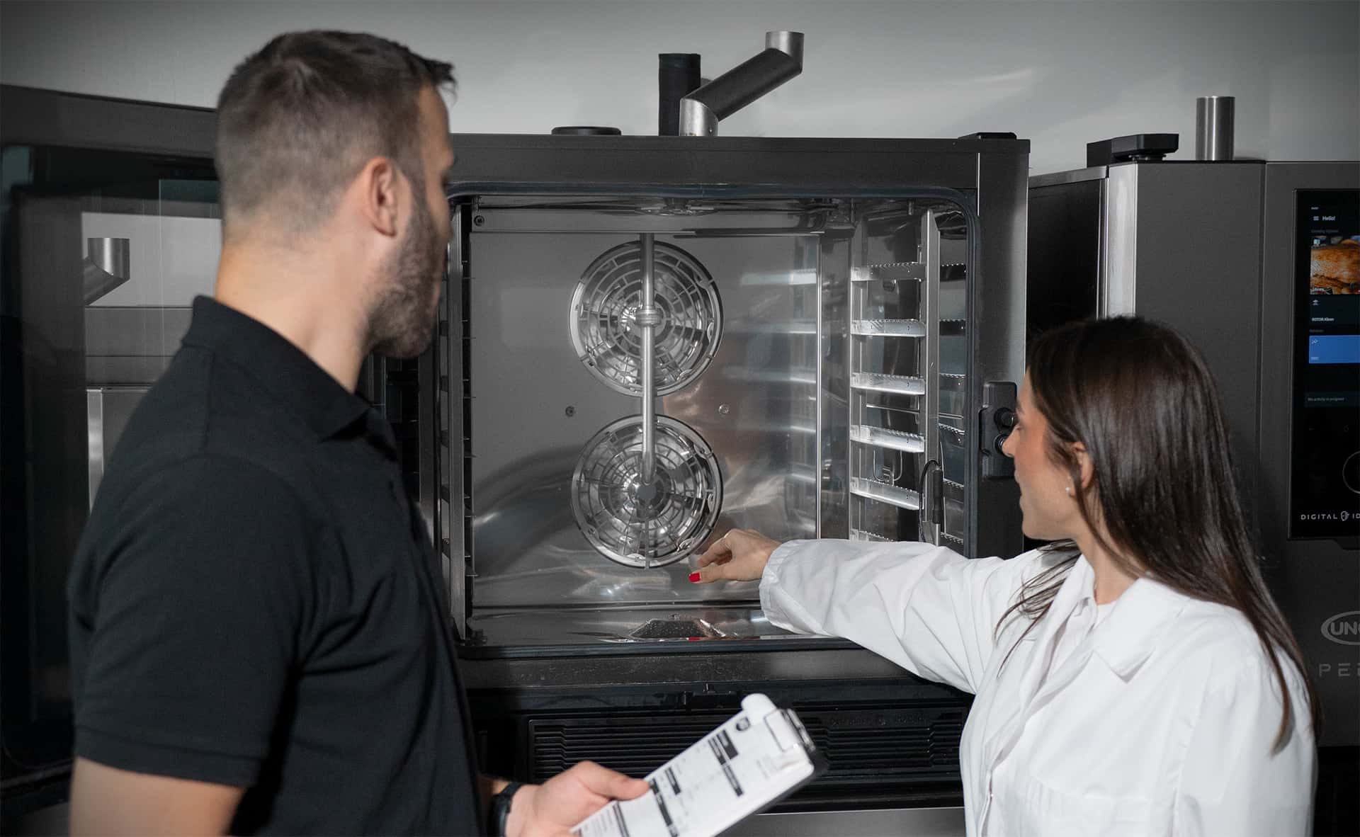 two unox technicians inspecting the spotless cooking chamber of a unox commercial oven