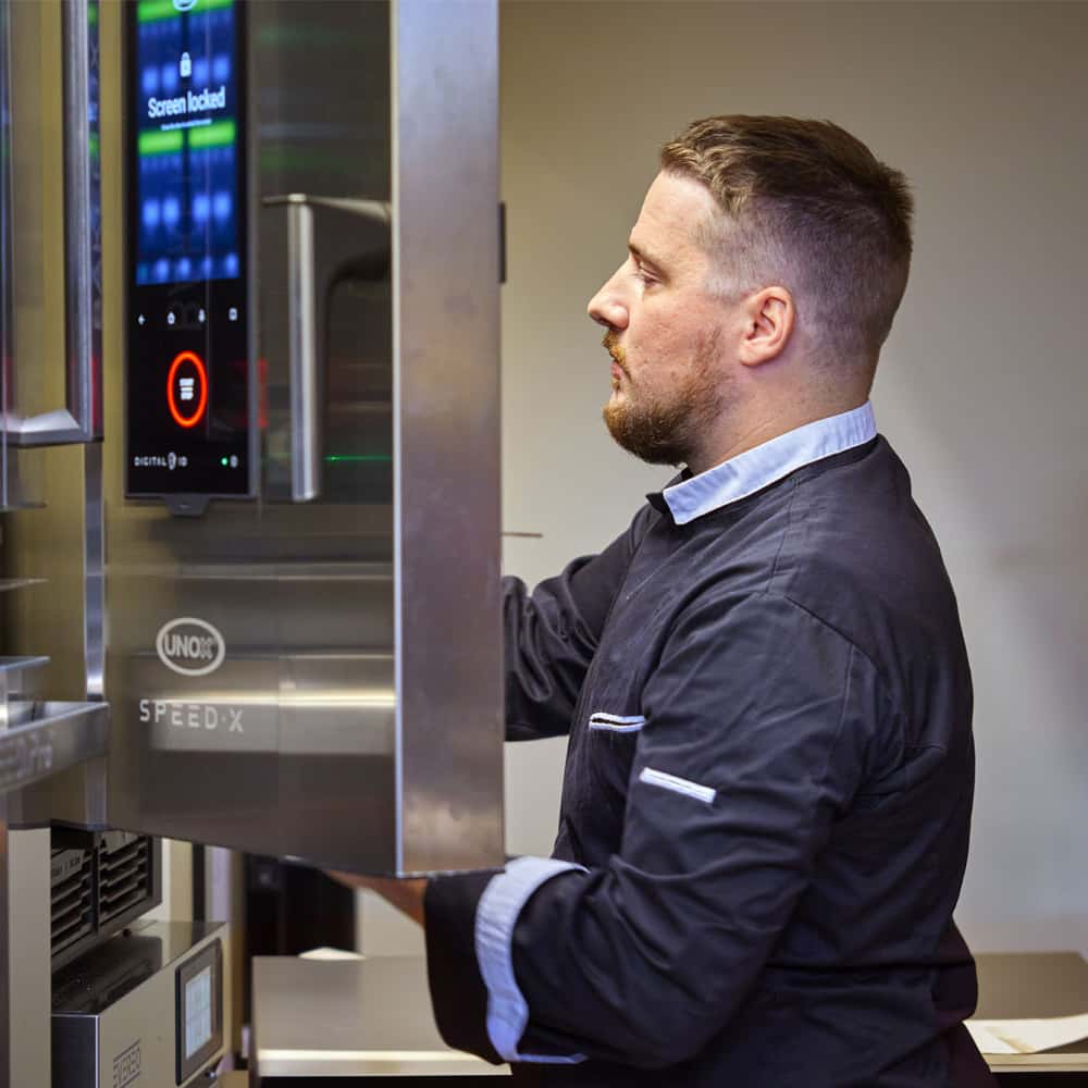 Male chef opening door of an Unox speed-x speed oven.