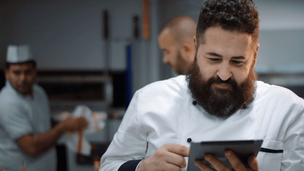 Executive chef in the kitchen who is using a tablet to control his smart commercial oven