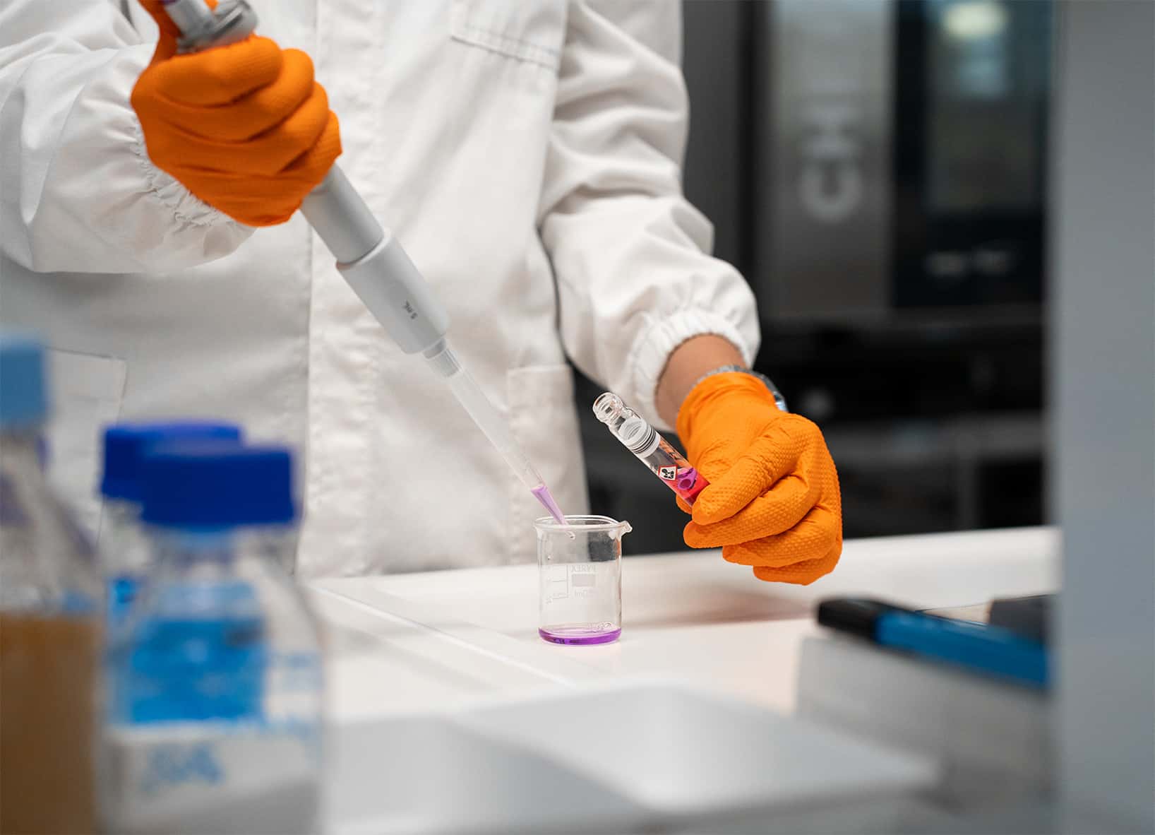 chemist pouring liquid into a beaker on a lab bench