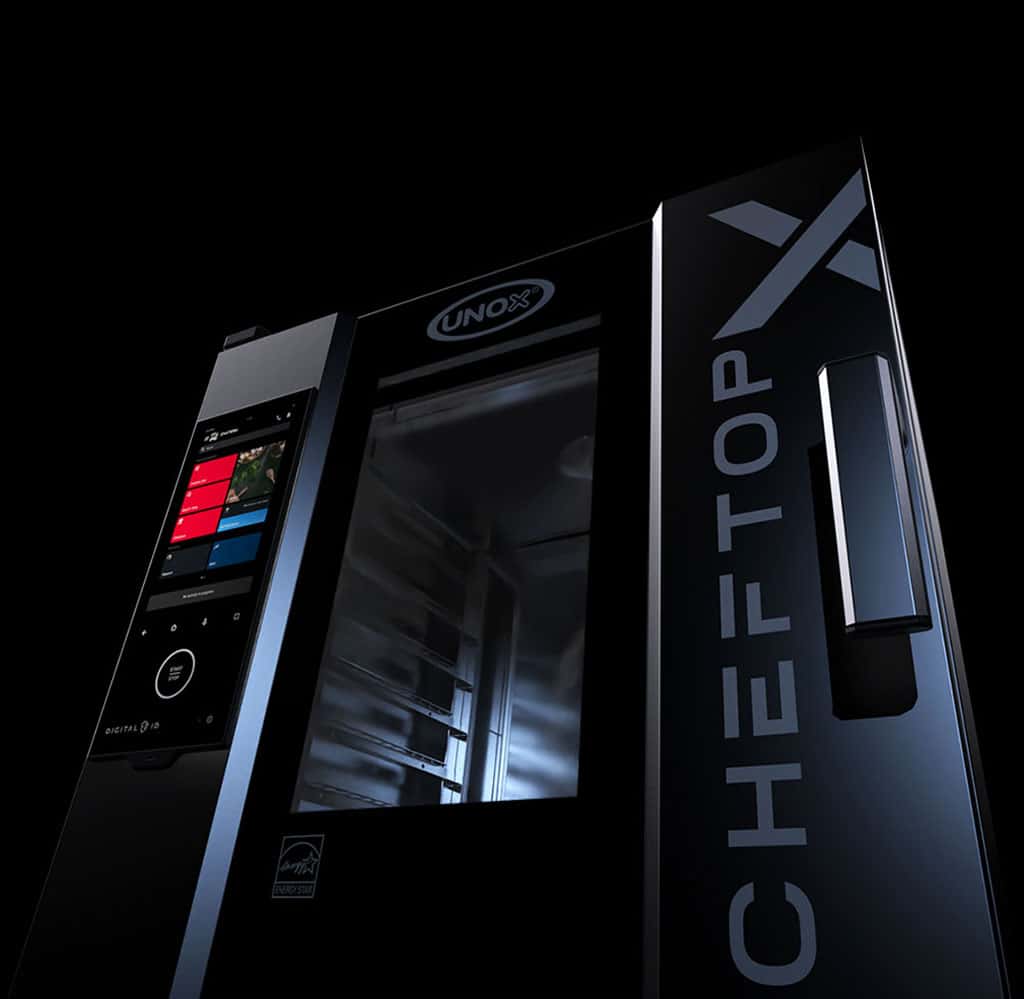 A dark, moody image of an Unox Cheftop X combi oven, lit so that only parts of the oven can be seen, such as the logo and digital display. 