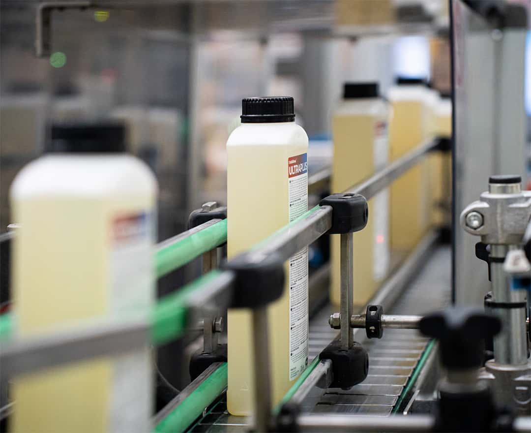 conveyor belt with unox detergent bottles aligned for packaging