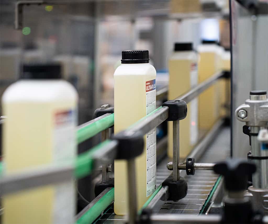 conveyor belt with unox detergent bottles aligned for packaging